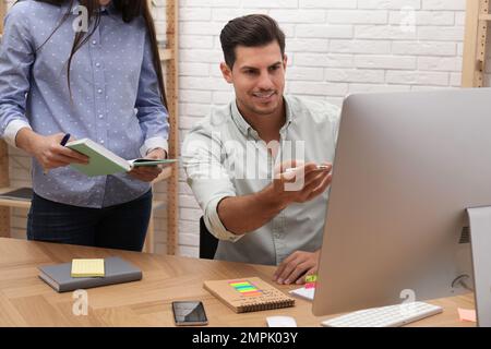 Colleagues making schedule using calendar in office Stock Photo