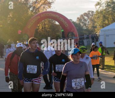 A group of runners participating in the Marine Corps Marathon 10K, slow down to recuperate after crossing the finish line, Arlington, Virginia, Oct. 30, 2022. The MCM10K is hosted the same day as the 47th Marine Corps Marathon, with the start of the race located at the National Mall, Washington, D.C.. Runners of all levels participated in the MCM10K; this particular course provided MCM hand-cyclists left-hand lanes with police escorts. Stock Photo