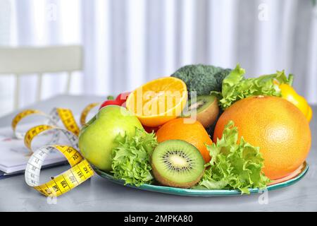 Measuring tape, vegetables and fruits on table. Diet plan from nutritionist Stock Photo