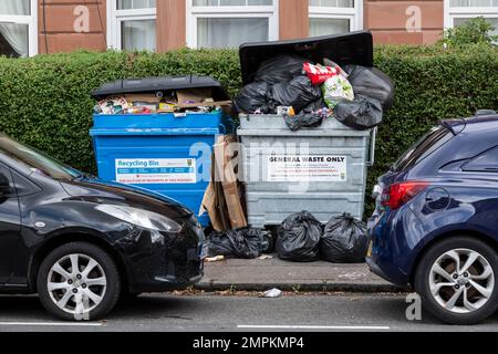 Overflowing domestic rubbish bin and black plastic bags on a pavement waiting to be cleared, Glasgow, Scotland, UK, Europe Stock Photo