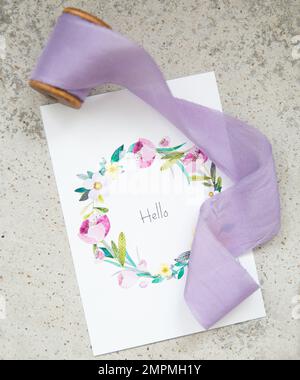 Purple silk ribbon and greeting card on concrete background Stock Photo