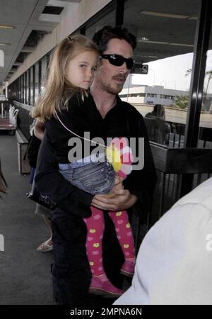 Actor Christian Bale carries his daughter Emmeline as he arrives with