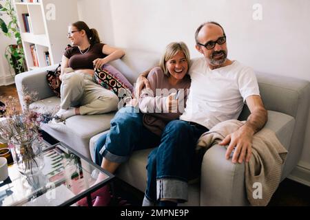 Man sitting with woman and daughter on sofa at home Stock Photo