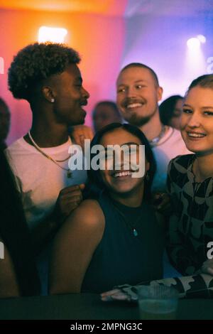 Happy young women and men dancing in club on weekend at night Stock Photo