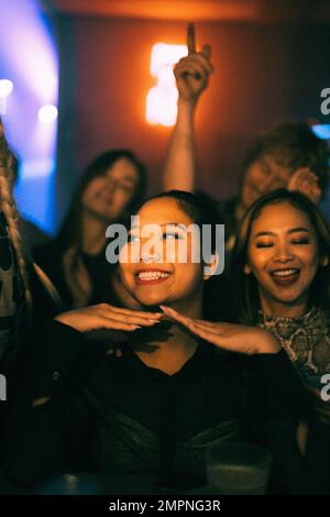 Happy young woman enjoying while dancing with friends in club at night during weekend Stock Photo