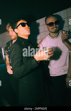 Non-binary person holding drink enjoying at nightclub with friends Stock Photo