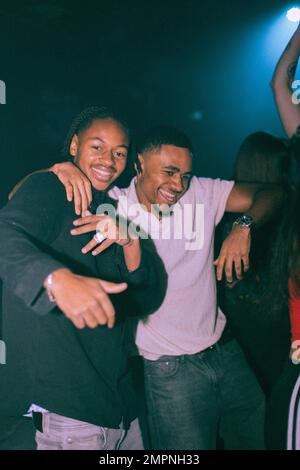 Portrait of cheerful young man dancing with male friend at nightclub Stock Photo