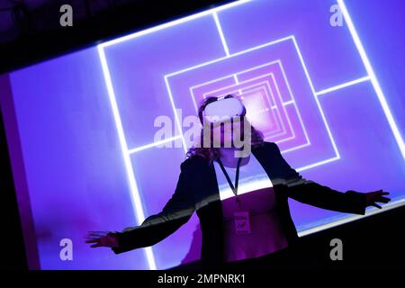 Young female entrepreneur wearing virtual reality glasses in front of projection screen at workshop Stock Photo