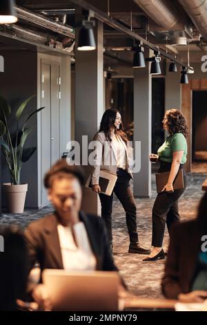 Multiracial business colleagues talking to each other while standing in office Stock Photo