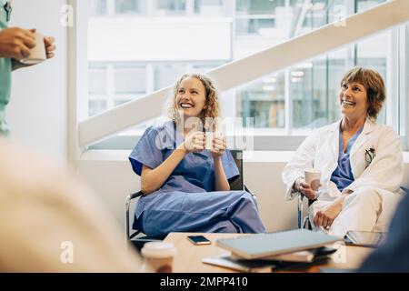 Happy female healthcare workers having coffee during break in hospital Stock Photo