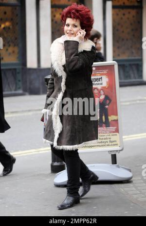 Wearing a shearling jacket and showing off her fire-engine red hair, Brazilian UK-based comedy actress and TV presenter Cleo Rocos (aka Cleopatra Rocos) is all smiles as she waves to photographers while chatting on her cellphone. London, UK. 01/24/11. Stock Photo