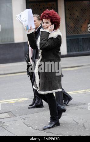 Wearing a shearling jacket and showing off her fire-engine red hair, Brazilian UK-based comedy actress and TV presenter Cleo Rocos (aka Cleopatra Rocos) is all smiles as she waves to photographers while chatting on her cellphone. London, UK. 01/24/11. Stock Photo