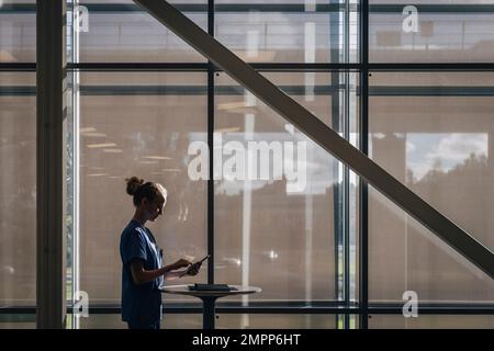 Side view of female nurse using tablet PC while standing by window at hospital Stock Photo