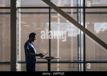 Side view of male physician using tablet PC while standing at table in hospital Stock Photo