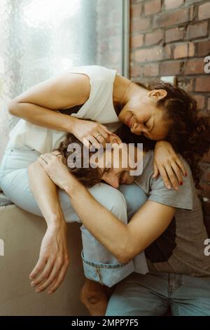 Two happy multiracial girlfriends sitting outdoors, drinking hot tea