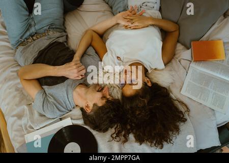 High angle view of couple lying with each other on bed at home Stock Photo