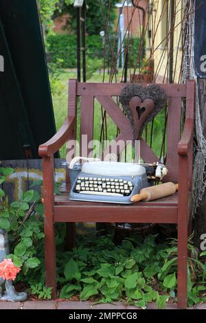 Old wooden chair with typewriter, metal heart and rolling pin Stock Photo