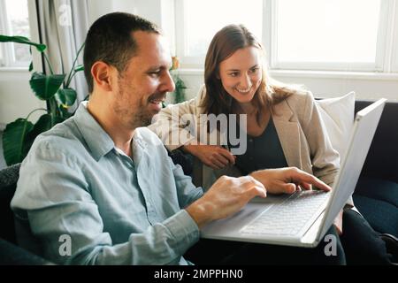 Happy business professionals working together on laptop while sitting at office Stock Photo