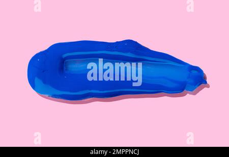 Blue paint Brush Stroke isolated on pink background. Acrylic paint Stock Photo
