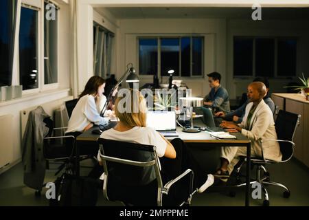 Business colleagues working late while sitting at desk in office Stock Photo