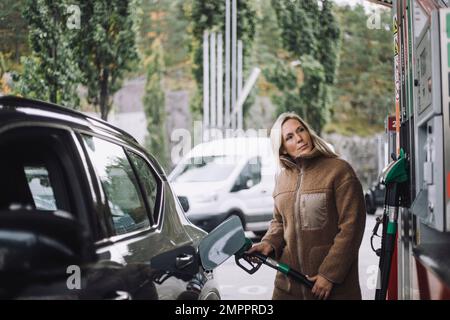 Woman pumping gas Stock Photo - Alamy