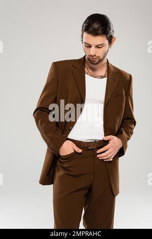 Trendy young man posing in brown suit isolated on grey Stock Photo