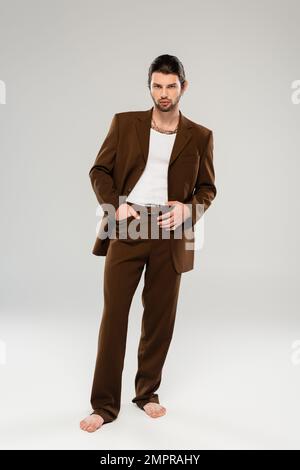 Full length of barefoot man in stylish suit posing on grey background Stock Photo