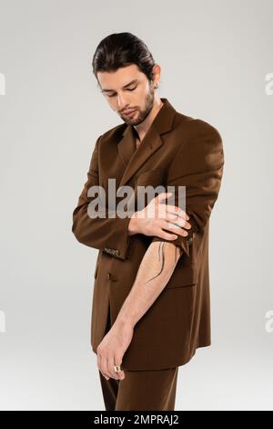 Bearded and tattooed man posing in jacket isolated on grey Stock Photo