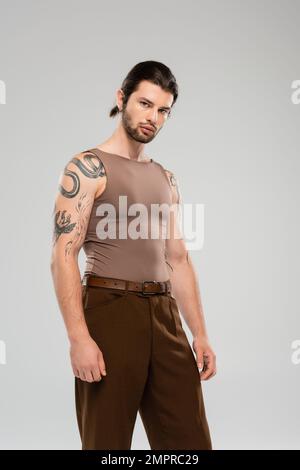 Bearded and tattooed man in sleeveless short looking at camera isolated on grey Stock Photo