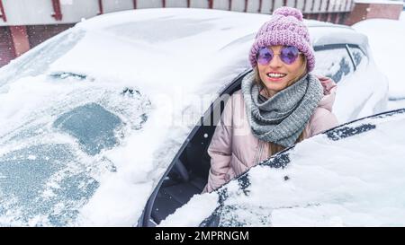 Woman in sunglasses getting into the car through the front door under the snow . High quality photo Stock Photo