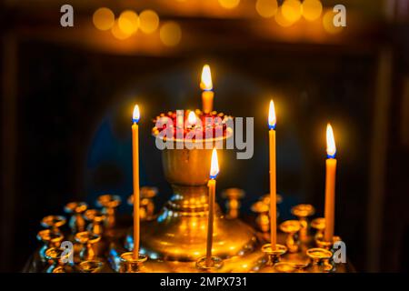 Lighted candles in gilded candlesticks and lamp in church. Blurred selective Focus Stock Photo