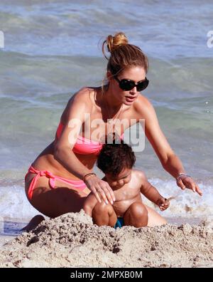 Supermodel Doutzen Kroes shows of her amazing figure in a pink bikini as she spends some quality time on the beach with 17 month old son Phyllon Joy Gorre.  The two swam and played in the sand. Miami Beach, FL. 18th June 2012. . Stock Photo