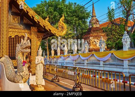 The vintage Naga serpent and Devata deity statues in front of historic Wat Inthakhin Sadue Muang with ancient brick stupa in background, Chiang Mai, T Stock Photo