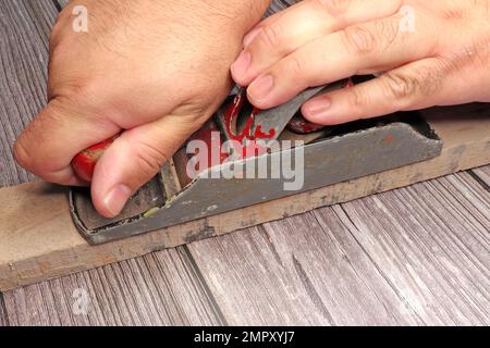 closeup of hands of a man working tool planed carpentry on workbench Stock Photo