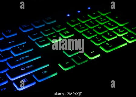 Fragment of the game keyboard with color backlight on black background. Close-up of computer keyboard. Selective focus. Stock Photo