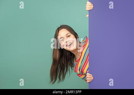 laughing kid behind blank blue paper with copy space for advertisement Stock Photo