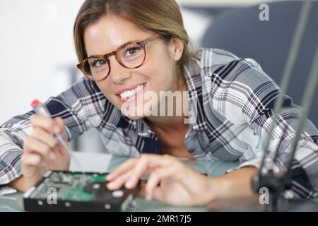 happy woman repairs a laptop using screw driver Stock Photo