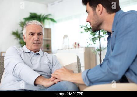 grown up son consoling senior parent Stock Photo