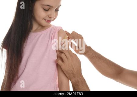 Man putting sticking plaster onto girl's arm on white background Stock Photo