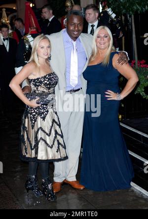 Vanessa Feltz (L), boyfriend Ben Ofoedu and daughter Allegra pose on a wet sidewalk on a rainy night after arriving at Fashion For The Brave.  The annual dinner, auction and fashion show fundraiser, benefitting groups which aid soldiers and veterans including The Household Cavalry Operational Casualties Fund, was held at The Dorchester.  London, UK. 10/26/10. Stock Photo