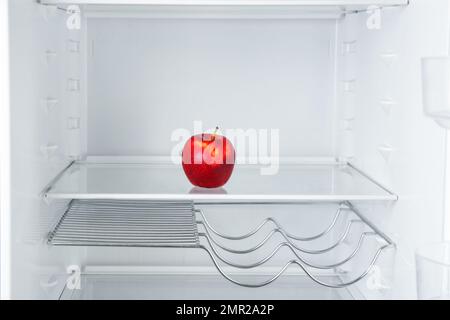 Fresh red apple on empty shelf in refrigerator Stock Photo