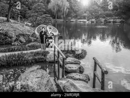 23-03-2015 A wedding couple (bride and groom) pose in a public park in the Kyosumi Teien garden. Japanese couple smiling and wearing traditional kimon Stock Photo