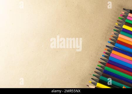 Colored pencils lined up on the right side of the image. isolated on brown background. Close-up. Stock Photo