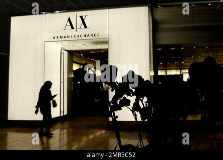 A shopper walks in front of the entrance to an Armani Exchange