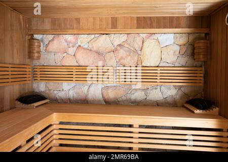 General view of sauna with wooden benches and stone wall Stock Photo