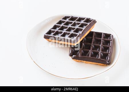 Waffles dipped in chocolate on plate, white background. Belgian waffles from store Stock Photo