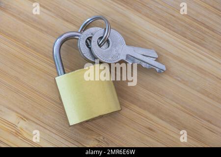 A Symbol of Safety: An Intriguing Shot of a Yellow Padlock and Keys on Wooden Background. Stock Photo