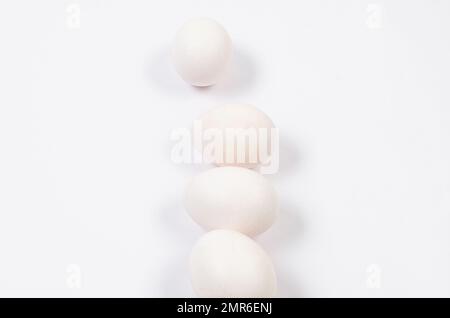 Fresh white chicken eggs close-up on white background. Group of four eggs. Stock Photo