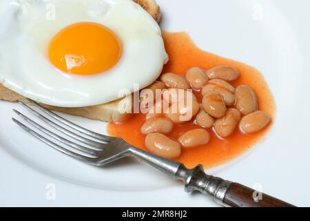 White beans with tomato sauce and fried egg on toast Stock Photo