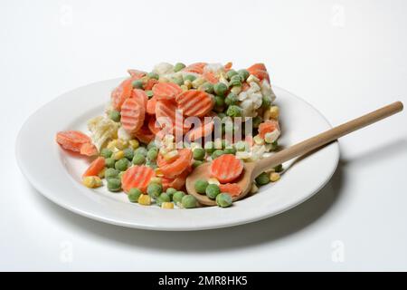 Frozen vegetables on plate with cooking spoon, frozen food Stock Photo